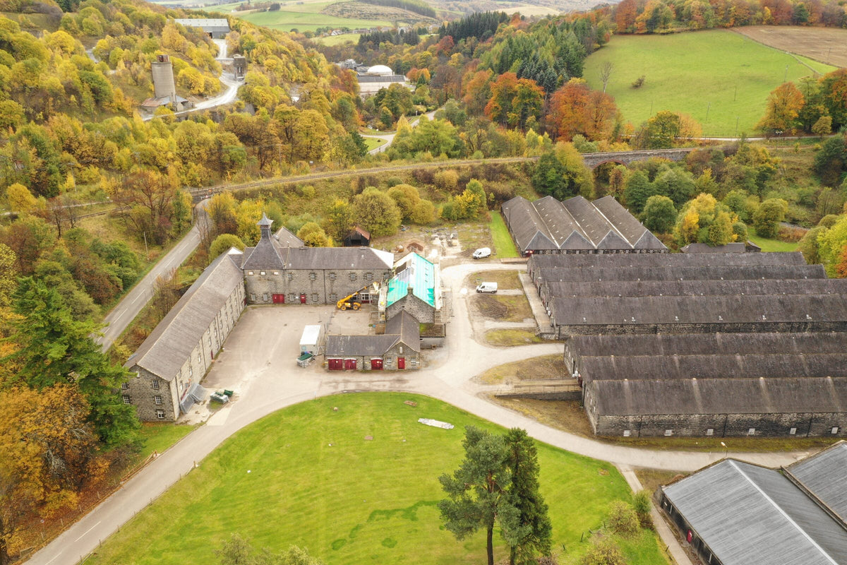 Parkmore Distillery's stone buildings and warehouses from the air in autumn, near Dufftown